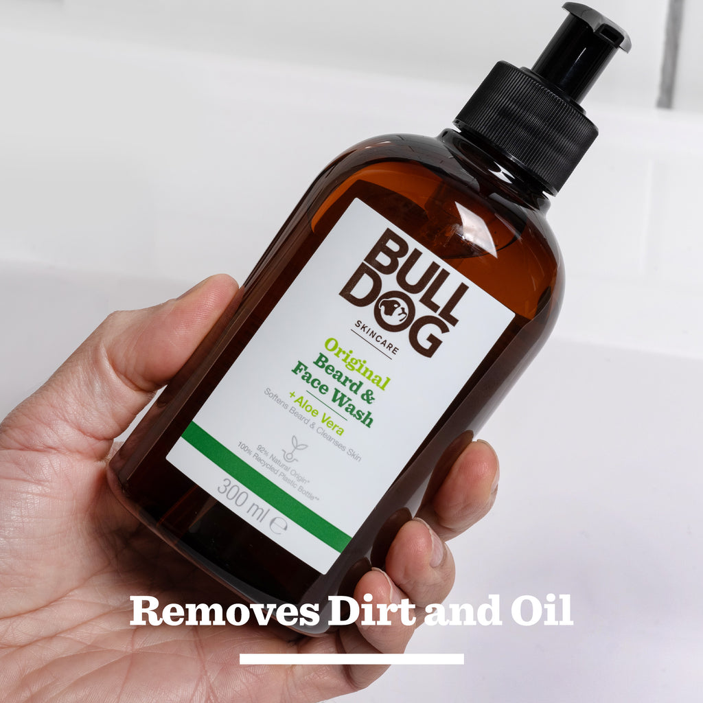 A hand holds a bottle of Original Beard & Face Wash. The text reads: Removes Dirt and Oil. This 300 ml beard & face wash uses natural origin ingredients to leave skin clean and hydrated.