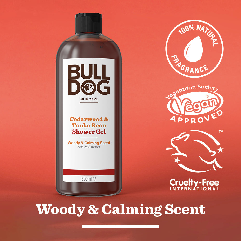 A bottle of Cedarwood & Tonka Bean Shower Gel sits on a red background, labeled 100% natural fragrance, vegan approved, and cruelty-free. Text reads: Woody & Calming Scent.