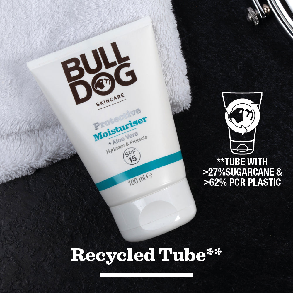 A tube of Protective Moisturiser with SPF 15 rests on a dark surface next to a white towel. Text notes its made from over 27% sugarcane, 62% recycled plastic, and natural ingredients for healthy skin.