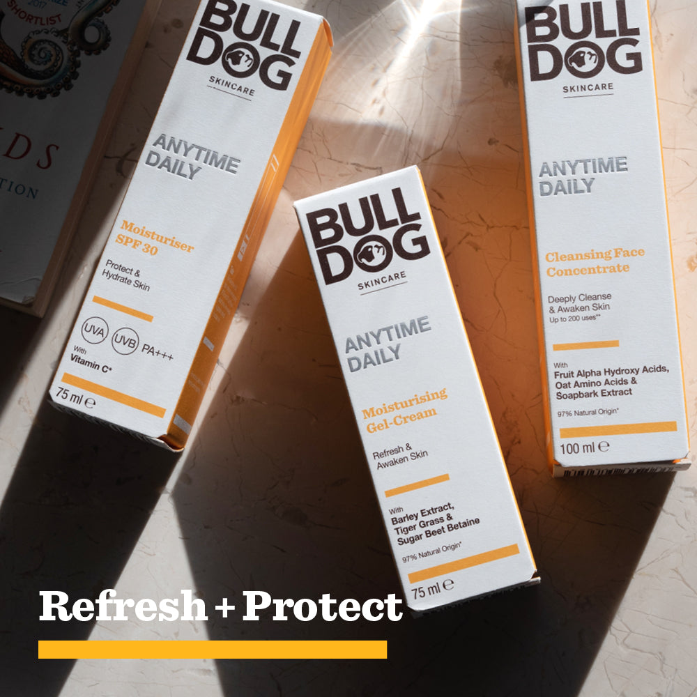 Three Bulldog Skincare products rest on a sunlit surface: Moisturiser SPF 30, Moisturising Gel-Cream, and Anytime Daily Cleansing Face Concentrate with natural origin ingredients. At the bottom, bold text reads: Refresh + Protect in white and yellow.