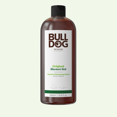 A brown bottle of Bulldog Original Shower Gel for men with a black cap. The 500ml label shows the brand name and notes its refreshing scent and natural ingredients.